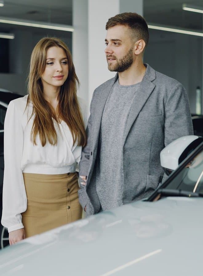 A couple at a car dealership showroom considering a new vehicle